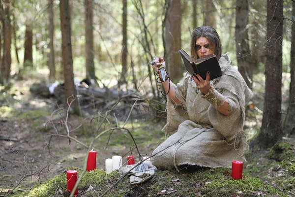 Um homem numa batina passa um ritual numa floresta escura. — Fotografia de Stock