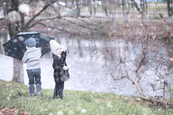 Kinder spazieren im Park im ersten Schnee — Stockfoto
