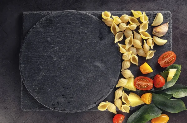 Nudelschalen auf schwarzem Stein. Tomaten und Lorbeerblätter mit Pallspi — Stockfoto
