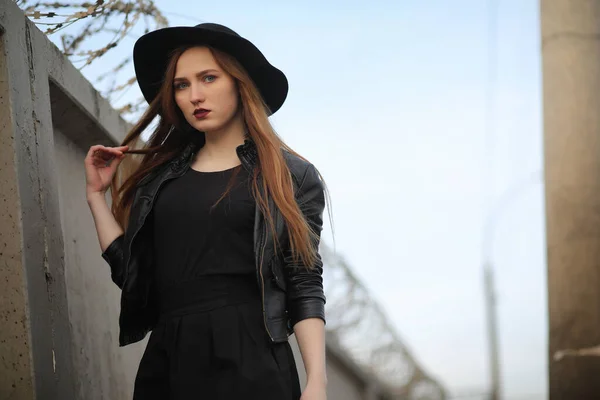 Una ragazza cammina lungo la strada della città in un gilet di pelle con un — Foto Stock