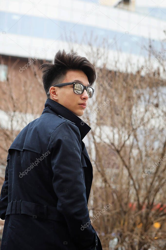 Asian young man in a coat on the street