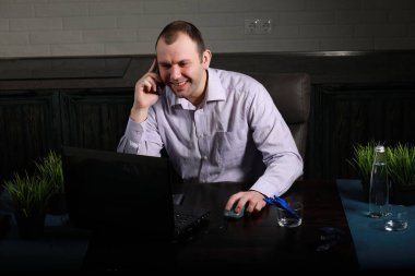 Masada oturan ve dizüstü bilgisayarda çalışan adam