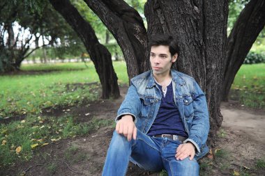 Genç bir adam öğle yemeği zamanında parkta yürür. Bir adam yürüyüşe çıktı. 