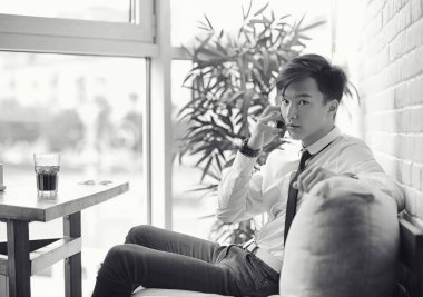 Genç Asyalı işadamı bir kafede bir ortak için bekliyor. Bu