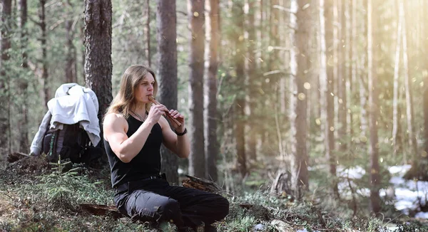 A musician with a tool in nature. A man is playing a flute in a — Stock Photo, Image