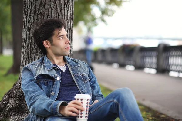 A young man walks in the park at lunch time. A man is on a walk