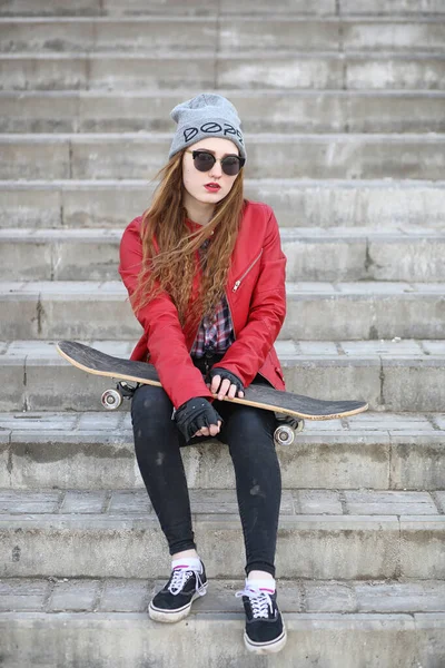 A young hipster girl is riding a skateboard. Girls girlfriends f — Stock Photo, Image