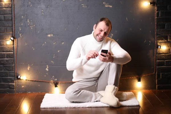 A man in a white sweater listens to music — Stock Photo, Image