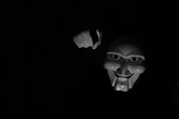 Máscara assustadora branca em um fundo preto com mão branca . — Fotografia de Stock