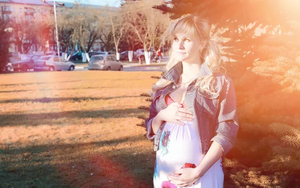 Беременная девушка на прогулке в парке. Девушка с животом в информаторе — стоковое фото