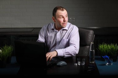 Masada oturan ve dizüstü bilgisayarda çalışan adam