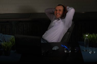 Masada oturan ve dizüstü bilgisayarda çalışan adam