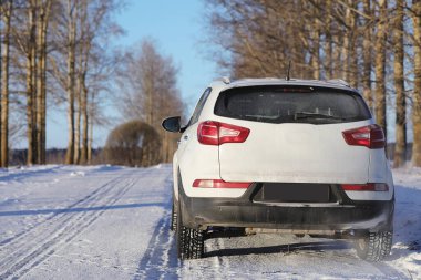 Beyaz araba kış parkında karla kaplı yolda. 