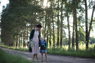Anne ve kızı yolda yürüyor.