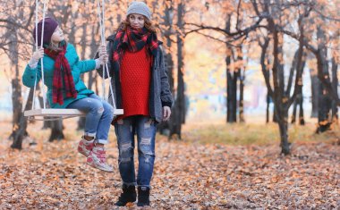 Kız sonbahar şehir parkında yaprak düşer. Genç güzel wi anne