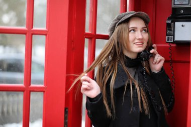 Güzel genç kız bir telefon kulübesinde. Kızı inci üzerinde konuşuyor