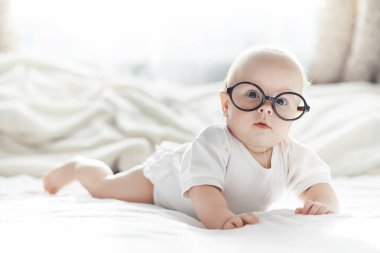 Yeni doğmuş bir bebek yumuşak bir yatakta gözlüklerle yatıyor..