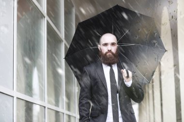 Takım elbiseli kel sakallı bir adam.