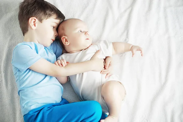 Los niños se acuestan en la cama junto al bebé recién nacido, hermanita . — Foto de Stock