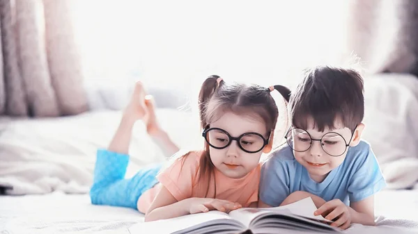 Los niños se acuestan en la cama junto al bebé recién nacido, hermanita . —  Fotos de Stock