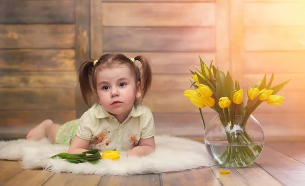 Un petit enfant avec un bouquet de tulipes jaunes. Un garçon avec un cadeau — Photo