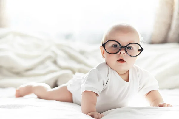 Een pasgeboren baby ligt op een zacht bed in een bril. — Stockfoto