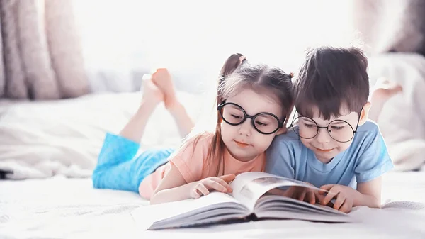 Kinderen liggen op het bed naast de pasgeboren baby, zusje. — Stockfoto