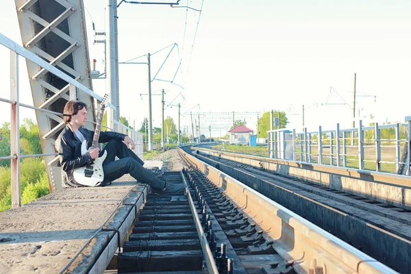 Homem com uma guitarra elétrica na paisagem industrial ao ar livre — Fotografia de Stock