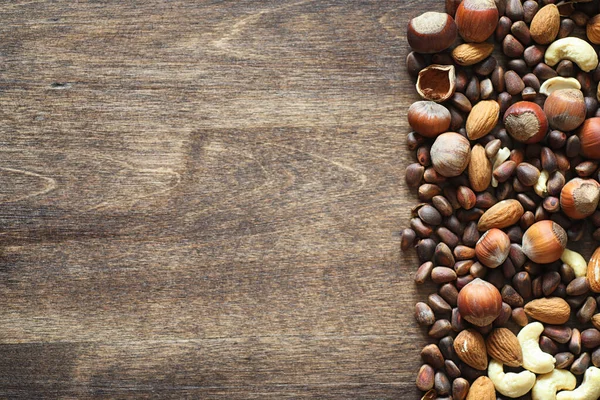 Olika nötter på ett träbord. Ceder, cashew, hasselnöt, walnu — Stockfoto