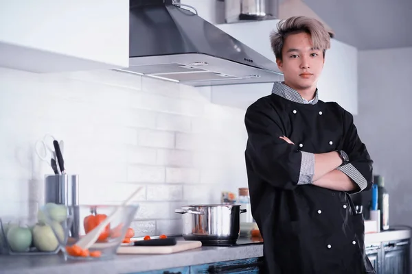 Asian cook in the kitchen prepares food in a cook suit