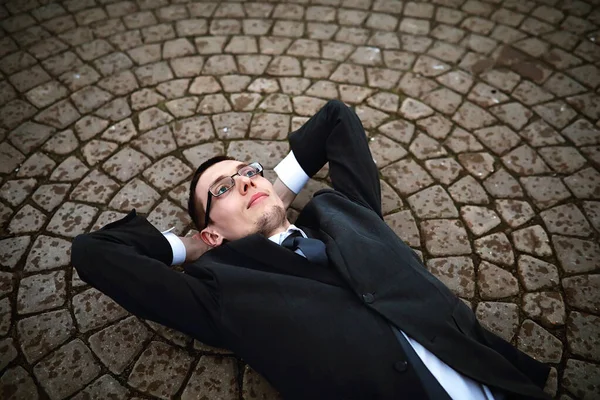 Мужчина в костюме лежит на кирпичном полу — стоковое фото