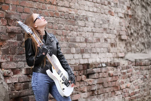 Uma menina músico de rock em uma jaqueta de couro com uma guitarra — Fotografia de Stock