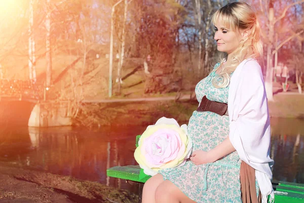 Schwangere Mädchen bei einem Spaziergang im Park. Mädchen mit einem Bauch in der Hand — Stockfoto