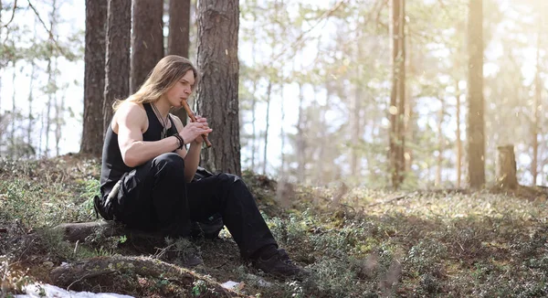 A musician with a tool in nature. A man is playing a flute in a — Stock Photo, Image