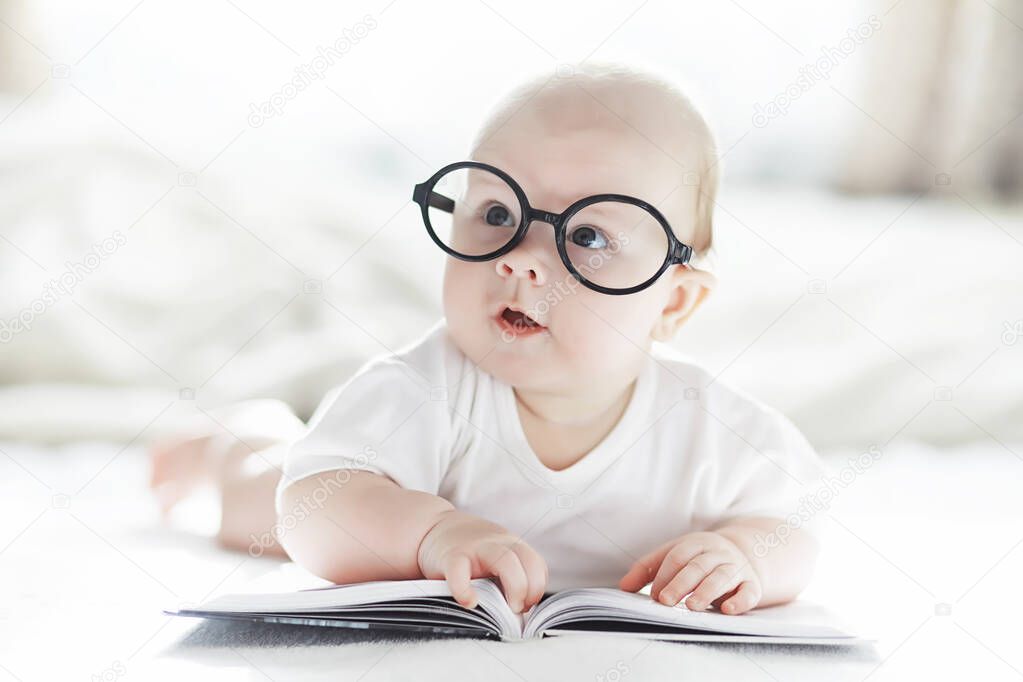 A newborn baby is lying on a soft bed in glasses.