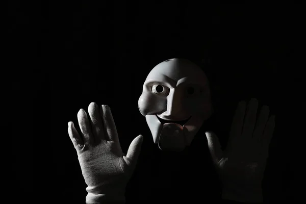 Maschera bianca spaventosa su uno sfondo nero con mano bianca . — Foto Stock