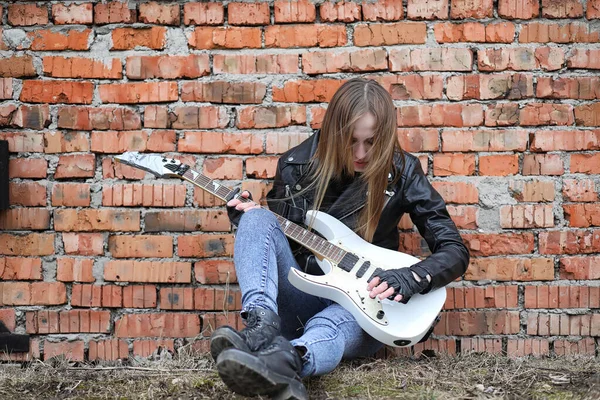 Uma menina músico de rock em uma jaqueta de couro com uma guitarra — Fotografia de Stock
