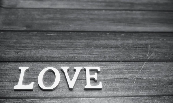 Slovo láska, které skládá se z bílých dřevěných písmen na dřevěné pozadí — Stock fotografie