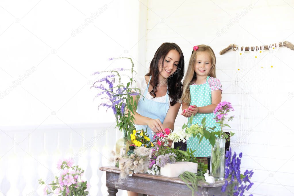 The mother and her little girl decorating a bouquet of dried flowers on a table