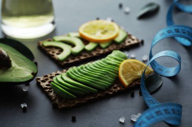 Avokado yemek tarifleri. Tahta kesme tahtasında servis edilen olgun yeşil avokado..