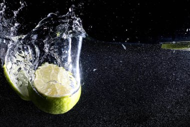 Olgun tatlı limonun üzerine su damlıyor. Metnin için kopyalama alanı olan taze kireç arkaplanı. Vejetaryen ve vejetaryen kavramı.