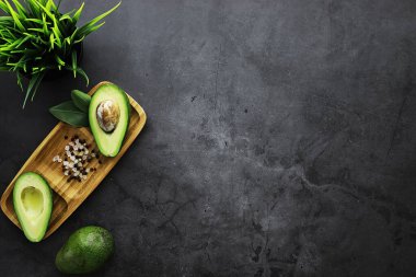 Avokado yemek tarifleri. Tahta kesme tahtasında servis edilen olgun yeşil avokado..