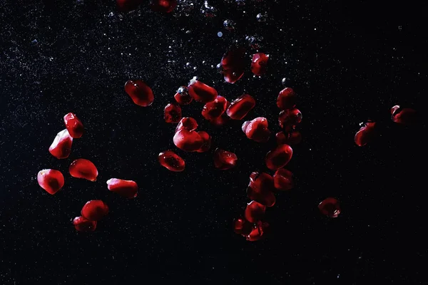 Olgun tatlı nar tohumlarına su damlaları düşer. Metnin için kopyalama alanı olan taze nar arkaplanı. Vejetaryen ve vejetaryen kavramı.