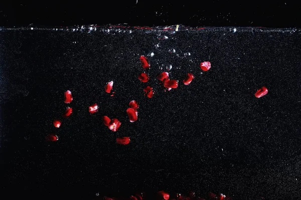 Olgun tatlı nar tohumlarına su damlaları düşer. Metnin için kopyalama alanı olan taze nar arkaplanı. Vejetaryen ve vejetaryen kavramı.