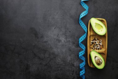 Avokado yemek tarifleri. Tahta kesme tahtasında servis edilen olgun yeşil avokado..