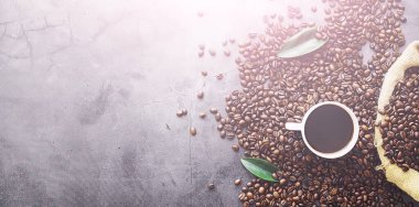 Bir poşet kahve. Kahve çekirdekleri masada kavrulmuş. Pişirmek için yapraklı kahve çekirdekleri.