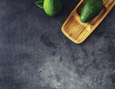 Avokado yemek tarifleri. Tahta kesme tahtasında servis edilen olgun yeşil avokado..