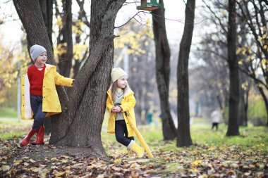 Çocuklar sonbaharda sonbahar parkında yürür