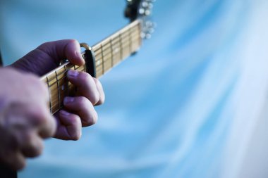 Sahnede telli bir enstrüman çalan sanatçı için akustik gitar. Capo 'lu siyah gitar. Müzik arkaplanı.