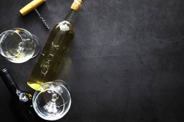 Masada bir bardak kırmızı şarap. Siyah şişe ve bir bardak şarap..